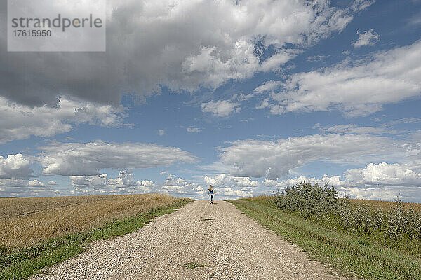 Frau geht auf einer Schotterstraße im ländlichen Saskatchewan; Saskatchewan  Kanada