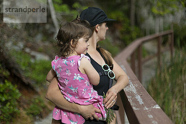 Eine Mutter hält ihre kleine Tochter während einer gemeinsamen Wanderung im Smuggler Cove Marine Provincial Park an der Sunshine Coast von BC  Kanada; British Columbia  Kanada