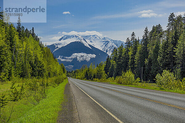 Highway durch Wälder zu einer majestätischen Bergkette; British Columbia  Kanada