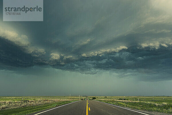 Eine Regenwand aus einem Gewitterkomplex wälzt sich während der Sturmsaison in der Tornado Alley den Highway hinauf; Kansas  Vereinigte Staaten von Amerika