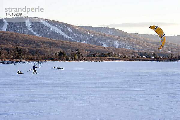 Ein Mann zieht zwei kleine Jungen hinter einem Drachen über einen zugefrorenen See; Canaan Valley  West Virginia.
