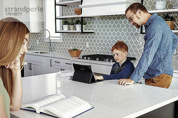 Vater hilft Sohn bei den Hausaufgaben in der Küche; Edmonton  Alberta  Kanada