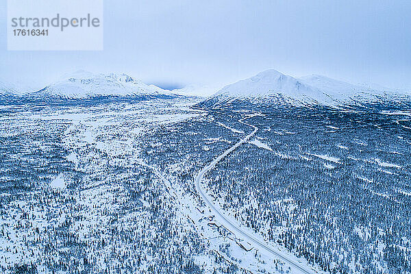 Der South Klondike Highway schlängelt sich durch die winterliche Yukon-Landschaft mit Wäldern und schneebedeckten Berggipfeln; Carcross  Yukon  Kanada