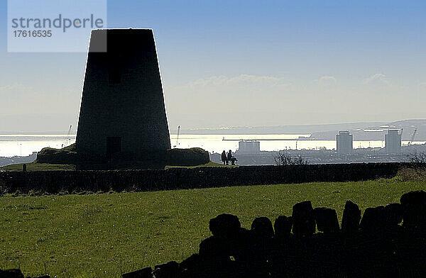 Silhouette der Old Flour Mill in den Cleadon Hills mit Menschen  die auf einer Bank mit Blick auf die Küste sitzen; South Shields  Tyne and Wear  England