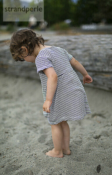 Mädchen im Vorschulalter steht am Strand und gräbt ihre Zehen in den Sand  Ambleside Beach in West Vancouver  BC  Kanada; West Vancouver  British Columbia  Kanada