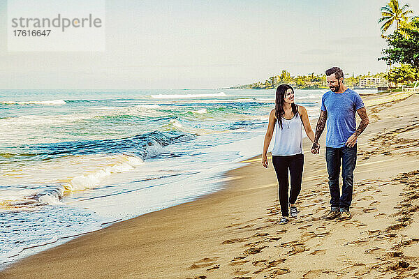 Ein Paar  das am Strand von Ka'anapali spazieren geht  sich an den Händen hält und miteinander spricht; Ka'anapali  Maui  Hawaii  Vereinigte Staaten von Amerika