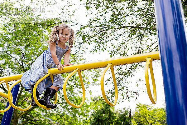 Junges Mädchen schaut von einem Klettergerät auf einem Spielplatz in die Kamera; Toronto  Ontario  Kanada