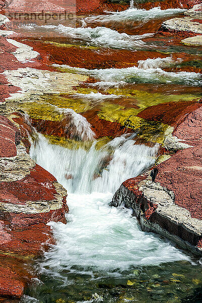 Ein rauschender Bach mit kleinen Wasserfällen zwischen roten Felswänden  Waterton Lakes National Park; Waterton  Alberta  Kanada