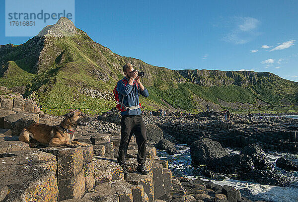 Ein junger Mann und sein Hund erkunden den Giant's Causeway in Nordirland  Vereinigtes Königreich.