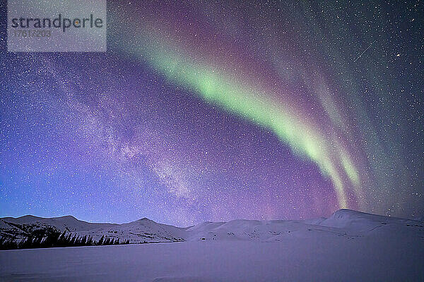 Aurora borealis (oder Nordlicht) über dem Dempster Highway und den schneebedeckten Bergen am Sternenhimmel im Winter; Yukon  Kanada