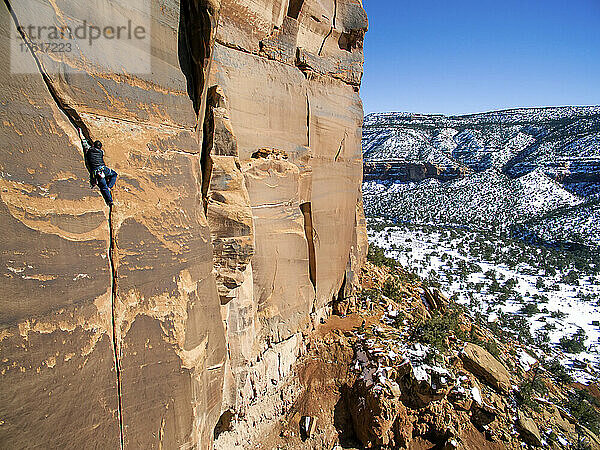 Ein Mann klettert in der Wüste von Colorado durch Sandsteinspalten.