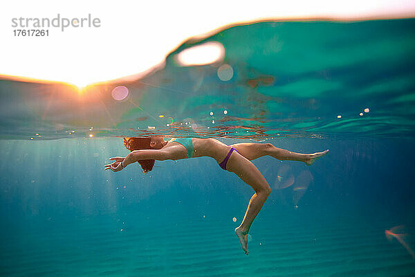 Eine Frau schwimmt in den klaren Gewässern von Baja.