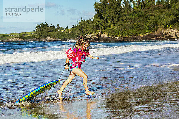 Ein junges Mädchen bringt ihr Bodyboard am D. T. Fleming Beach ans Ufer  nachdem sie eine Welle geritten hat; Kapalua  Maui  Hawaii  Vereinigte Staaten von Amerika