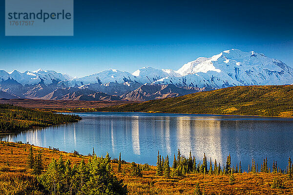 Mount Denali (McKinley) spiegelt sich im Wonder Lake  umgeben von warmen Herbstfarben auf Tundra-Hügeln; Denali National Park and Preserve  Interior Alaska  Alaska  Vereinigte Staaten von Amerika