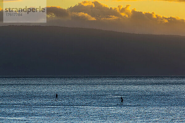 Silhouetten von zwei Stand-up-Paddleboardern bei Sonnenuntergang.