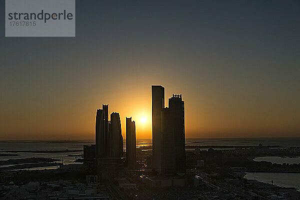 Blick auf die silhouettierten Hochhäuser entlang der Küste des Persischen Golfs bei Sonnenuntergang; Abu Dhabi  Vereinigte Arabische Emirate