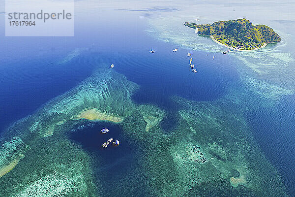 Luftaufnahme von Booten  die in den Gewässern um eine Insel und eine vorgelagerte Lagune im Komodo-Nationalpark fahren; Ost-Nusa Tenggara  Kleine Sunda-Inseln  Indonesien
