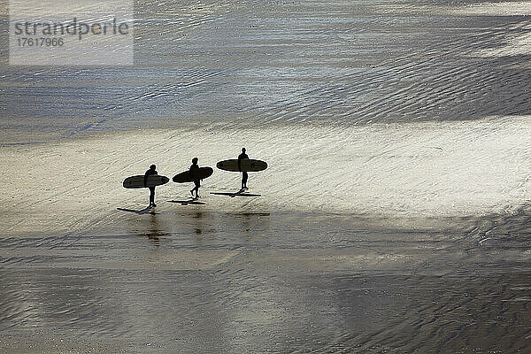 Surfer in Silhouette  die auf die Brandung zugehen; Saunton Sands  Barnstaple  Devon  England  Großbritannien  Vereinigtes Königreich.