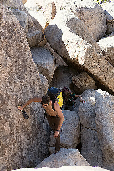 Kletterer klettern auf Felsbrocken zum Ausgangspunkt einer Klettertour im Joshua Tree National Park.