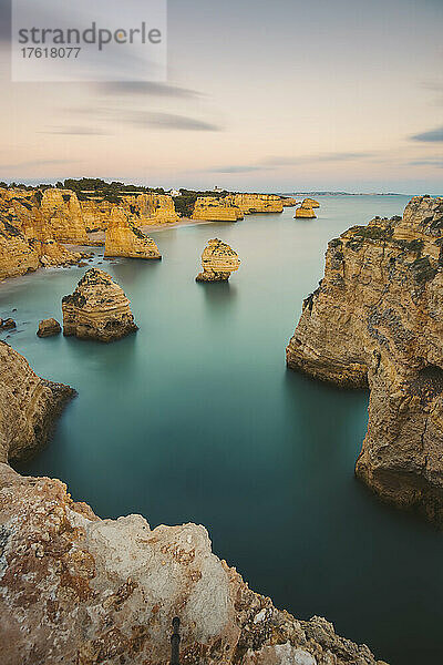 Ikonische Felsformationen und türkisfarbenes Wasser des Atlantischen Ozeans am Praia da Marinha entlang der Atlantikküste in Caramujeira  Teil der Gemeinde Lagoa  bei Sonnenuntergang; Algarve  Bezirk Faro  Portugal