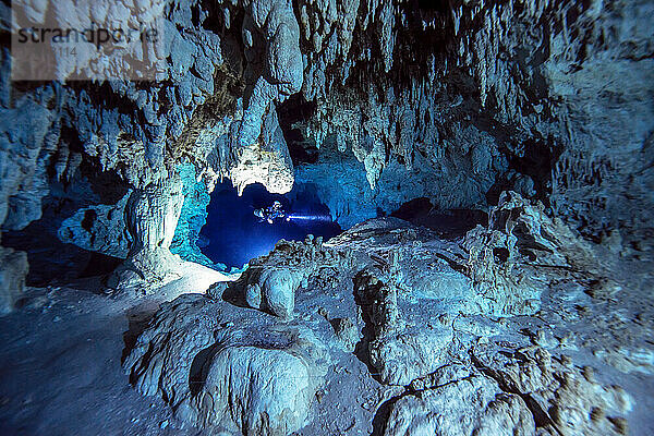 Ein Höhlentaucher durchquert einen wunderschönen weißen Kalksteinabschnitt tief im Inneren eines Höhlensystems.