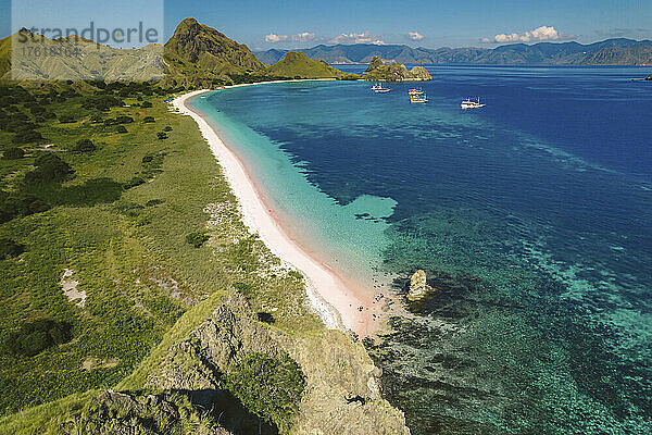 Luftaufnahme eines weißen Sandstrands entlang der Küste der Insel Padar im Komodo-Nationalpark mit vor der Küste vertäuten Booten; Ost-Nusa Tenggara  Kleine Sunda-Inseln  Indonesien