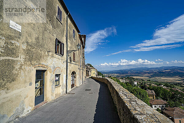 Mittelalterliche Gebäude und Steinmauern säumen die Allee mit Blick auf die Landschaft in der historischen Altstadt von Volterra; Volterra  Toskana  Italien