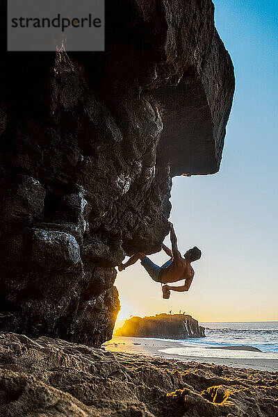 Ein Mann beim Bouldern am Strand von Oahu.