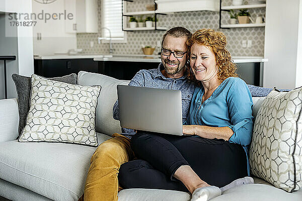 Ehepaar  das zu Hause auf einer Couch sitzt und seinen Laptop benutzt; Edmonton  Alberta  Kanada