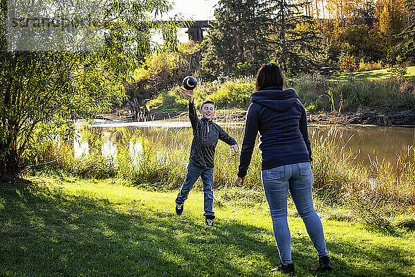 Mutter wirft mit ihrem Sohn an einem schönen Herbsttag in einem Stadtpark einen Fußball; St. Alberta  Alberta  Kanada