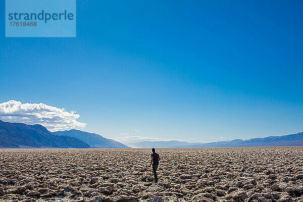 Ein Mann  der über die rissigen Wüstenebenen im Death Valley läuft.