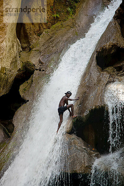 Ein Mann erklimmt den Wasserfall im Basin Bleu.
