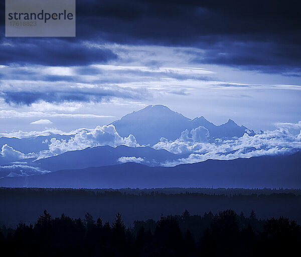 Die Gipfel des Mount Baker mit Wolken und Silhouetten der Wälder im Tal; Surrey  British Columbia  Kanada
