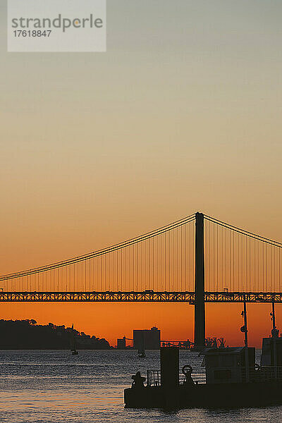 Silhouette der Brücke 25 de Abril über den Tejo  die Lissabon und Almada bei Sonnenuntergang verbindet; Lissabon  Estremadura  Portugal