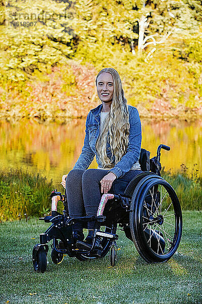 Junge querschnittsgelähmte Frau in ihrem Rollstuhl in einem Park an einem schönen Herbsttag; Edmonton  Alberta  Kanada