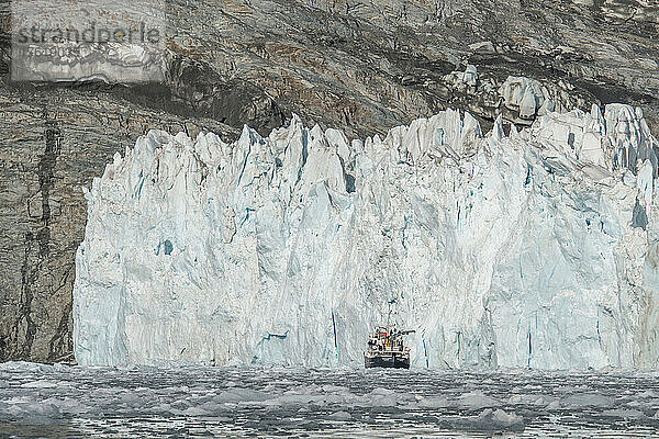 Schiff vor der eisigen Wand eines Gezeitengletschers an der Küste der Insel Südgeorgien mit dem kabbeligen Meereiswasser des Südlichen Ozeans; Südgeorgien  Antarktis