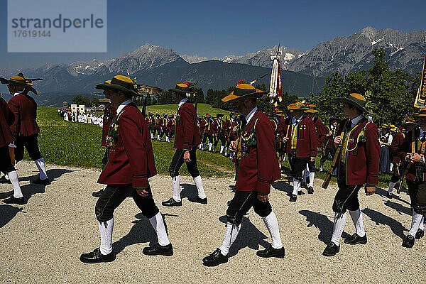 Der Festzug zum Herz-Jesu-Fest zieht in eine große Wiese ein  die vom Karwendelgebirge überragt wird; Österreich.