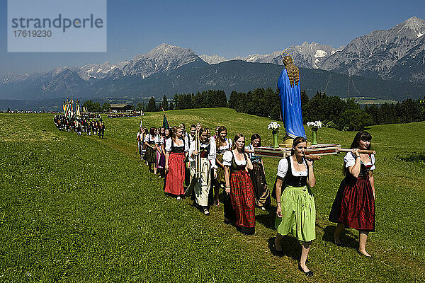 Der Festzug zum Herz-Jesu-Fest zieht in eine große Wiese ein  die vom Karwendelgebirge überragt wird; Österreich.