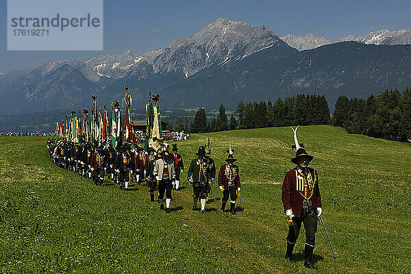 Der Festzug zum Herz-Jesu-Fest zieht in eine große Wiese ein  die vom Karwendelgebirge überragt wird; Österreich.