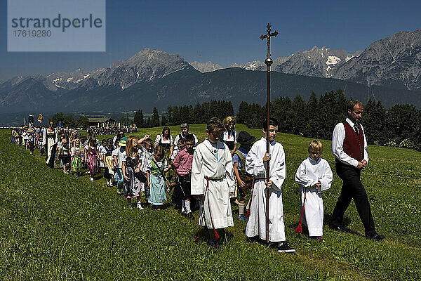 Der Festzug zum Herz-Jesu-Fest zieht in eine große Wiese ein  die vom Karwendelgebirge überragt wird; Österreich.