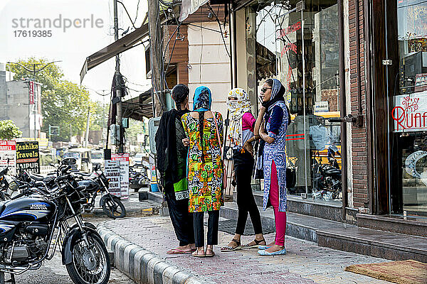 Gruppe junger Frauen  die zusammen auf einem Bürgersteig entlang einer Straße in einer Stadt in Indien stehen; Amritsar  Punjab  Indien