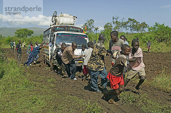 Bus  der nach heftigen Regenfällen auf einer schlammigen Straße in der Nähe des Ruma-Nationalparks bei Homa Bay gezogen wird; Kenia