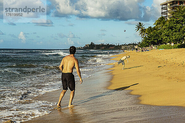Ein Vater und sein Sohn werfen einen Fußball am Strand von Ka'anapali bei Sonnenuntergang; Ka'anapali  Maui  Hawaii  Vereinigte Staaten von Amerika