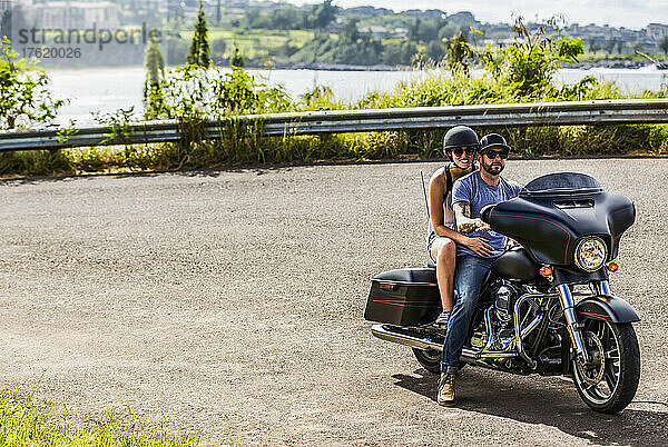 Ein Paar sitzt auf einem Motorrad an einer Abzweigung des Honoapiilani Highway in Nordwest-Maui und posiert für die Kamera; Maui  Hawaii  Vereinigte Staaten von Amerika