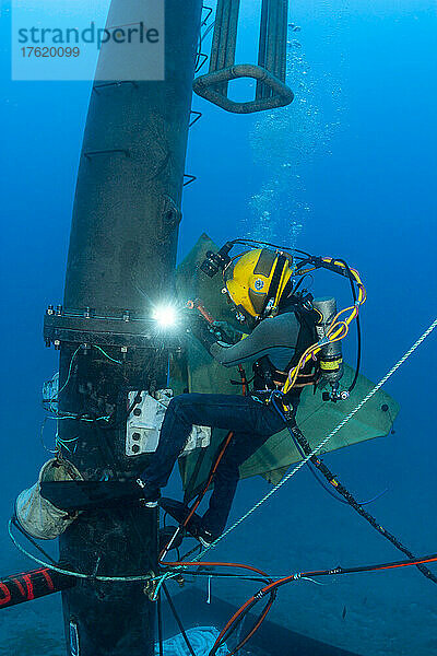 Ein Berufstaucher mit Schutzhelm schweißt ein Teil einer Wellenenergieboje unter Wasser vor Oahu  Hawaii; Oahu  Hawaii  Vereinigte Staaten von Amerika