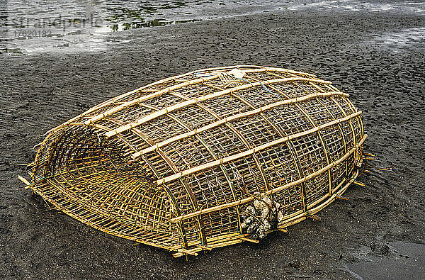 Eine traditionelle Fischreuse aus geflochtenem Bambus an einem Strand aus schwarzem Vulkansand; Manado  Nordsulawesi  Indonesien