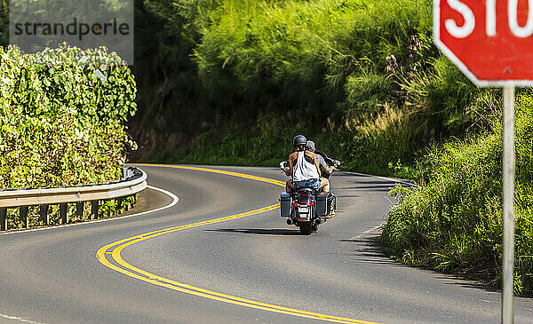 Ein Motorrad fahrendes Paar auf dem Honoapiilani Highway  einer kurvenreichen Straße entlang der Küstenlinie von Nordwest-Maui; Maui  Hawaii  Vereinigte Staaten von Amerika