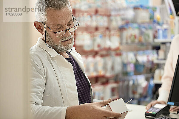 Apotheker liest Anweisungen auf der Medikamentenschachtel in der Apotheke