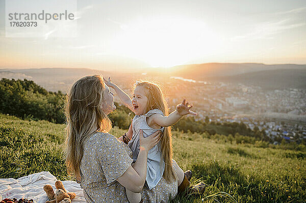 Glückliche Mutter und Tochter verbringen Zeit in der Natur bei Sonnenuntergang
