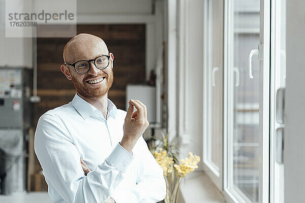 Happy bald working man wearing eyeglasses gesturing in office